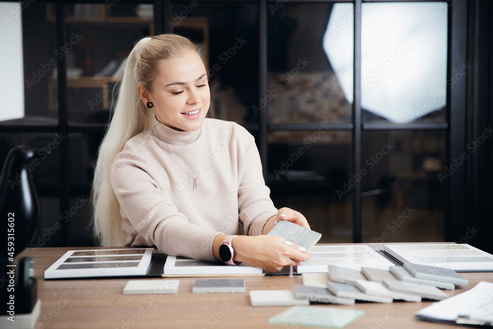 Young woman professional designer chooses ceramic tiles for apartment design project on workplace Young woman professional designer chooses ceramic tiles for apartment design project on workplace