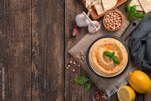 Hummus with sesame, garlic and lemon on a wooden background. Healthy vegetable oriental dishes, vegetarian food. Side view, space for copying.