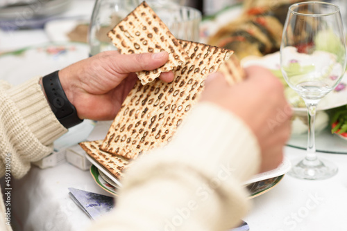 Jewish family celebrating Passover.Jewish man blessing and breaking matzah as they celebrate Seder. The feast is celebrated on the first night of Passover. photo