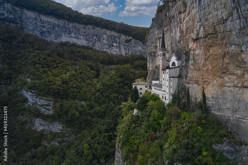 The unique Sanctuary Madonna della Corona church in the rock. Aerial view of the church on the sheer cliff. Italian church at high altitude in the Alps. The sanctuary is high in the mountains of Italy