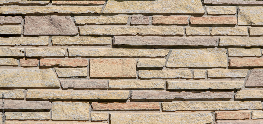 Sandstone building wall constructed in multi-colored, different sized stones in a pleasing horizontal pattern. Sandstone building wall constructed in multi-colored, different sized stones in a pleasing horizontal pattern.