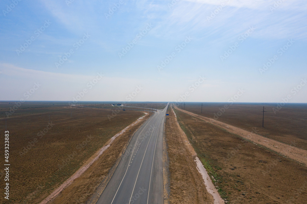amazing panorama of the steppe and a straight line of the highway through the sandy desert in the Astrakhan region in Russia.