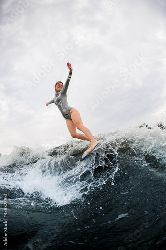 Fabulous view on huge splashing wave and energy woman on wakesurf rides down on it