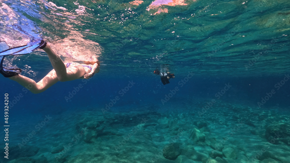Underwater split photo of unidentified woman snorkeling in volcanic white rock caves with emerald clear sea