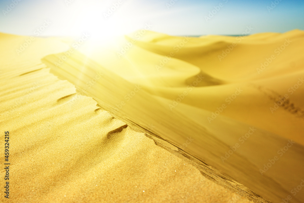 Yellow sunset in sand dunes with footprints.