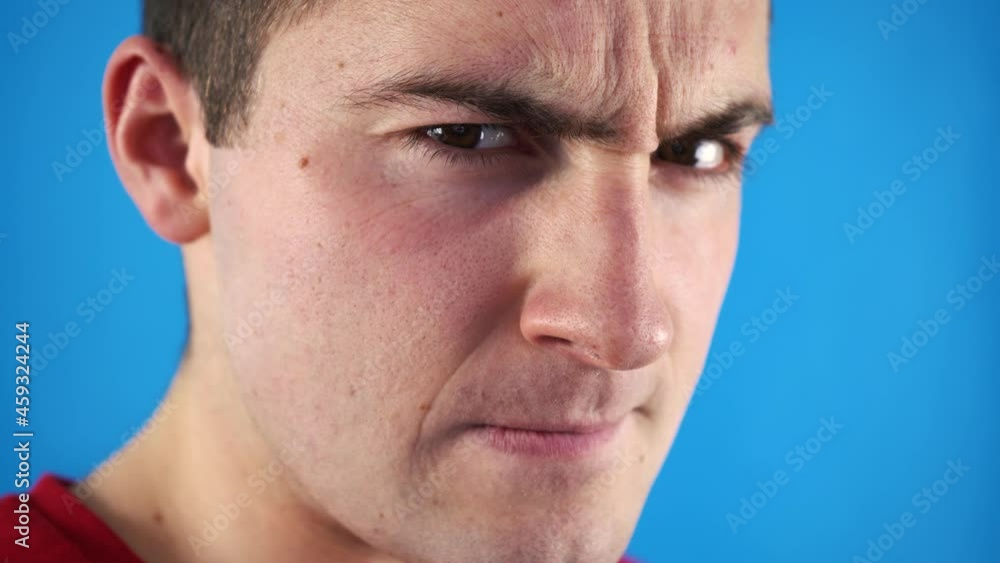 man looking at the camera with suspicion on a blue background man looking at the camera with suspicion on a blue background