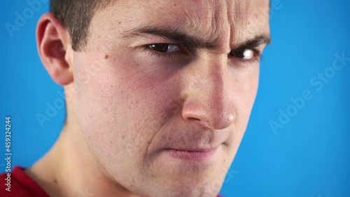 man looking at the camera with suspicion on a blue background
