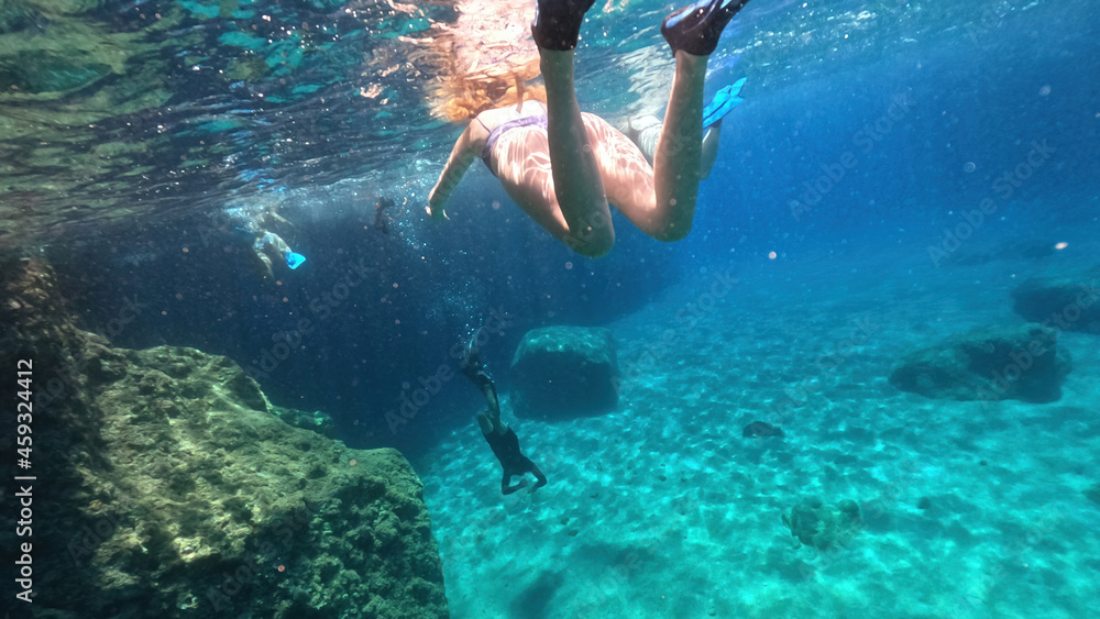 Underwater split photo of woman diver, snorkelling in beautiful paradise volcanic white rock famous Kleftiko with emerald crystal clear sea and caves, Milos island, Cyclades, Greece