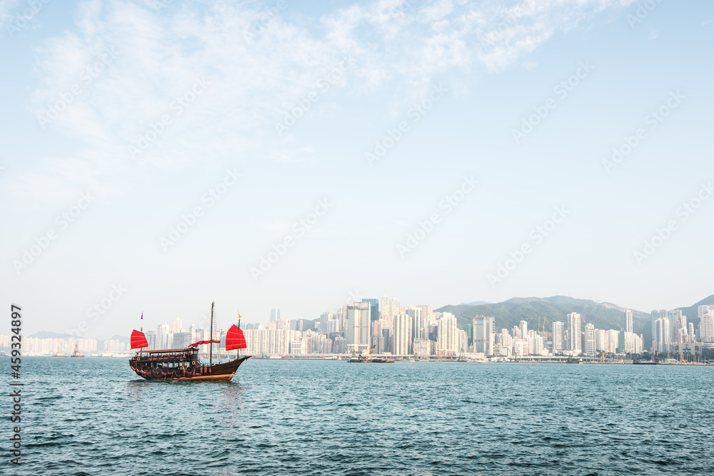 Obraz premium Traditional Chinese Junkboat sailing. Views of the skyscrapers background.