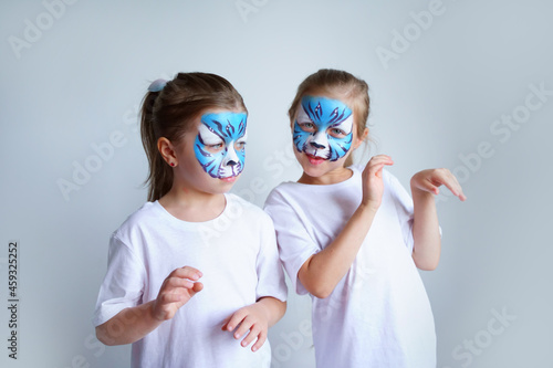 Two sister girls with aqua makeup in the form of a blue water zodiac tiger depict a tiger on a white background, a conceptual symbol of the new 2022 year. High quality photo