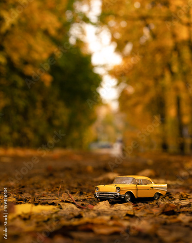 Fotografi a small yellow model of an old car against the background of an autumn yellow landscape