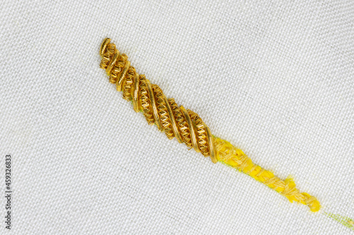 sample of raised goldwork embroidery in progress, smooth purl and bright check threads with felt padding for couching underneath to create three dimensional stitching photo