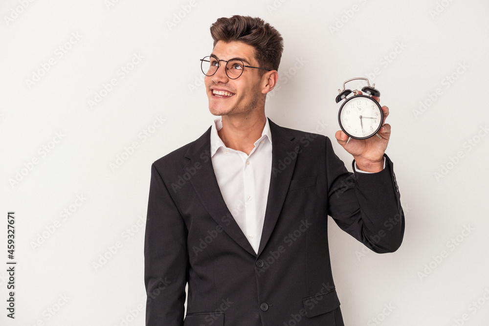 Young business caucasian man holding alarm clock isolated on white background dreaming of achieving goals and purposes Young business caucasian man holding alarm clock isolated on white background dreaming of achieving goals and purposes