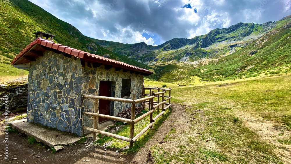 Mountain cabin in a beautiful green valley surrounded by high and stunning mountains Mountain cabin in a beautiful green valley surrounded by high and stunning mountains
