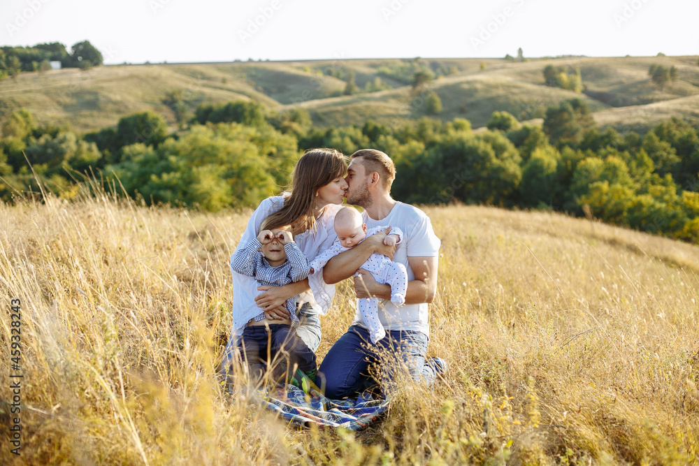 mom dad and two sons posing on the background of nature in a field with tall grass mom dad and two sons posing on the background of nature in a field with tall grass