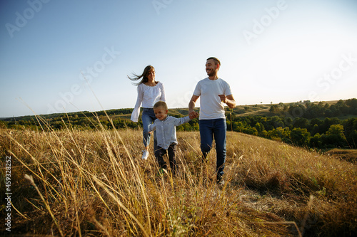 mom and dad hold their son s hands and run across the field