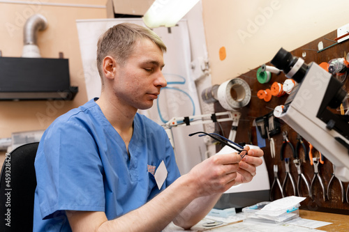 Professional optometrist specialist in workshop. Ophtalmologist fixing new glasses. photo