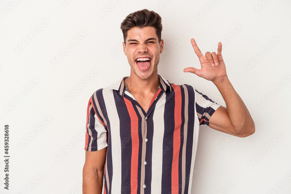 Naklejka premium Young caucasian man isolated on white background showing a horns gesture as a revolution concept.