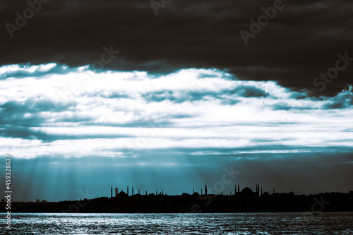 Silhouette of Istanbul at sunset with dramatic cloudy sky and sunlight beams. photo