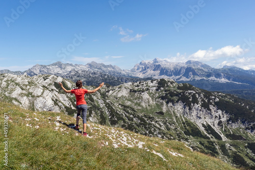 Woman with arms raised in the air enjoying an amazing view of mountain peaks