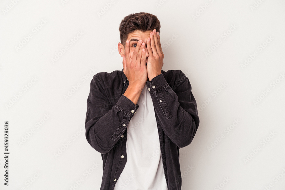 Young caucasian man isolated on white background blink through fingers frightened and nervous. Young caucasian man isolated on white background blink through fingers frightened and nervous.
