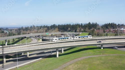 Aerial tracking shot of MAX light trail passenger train traveling on train tracks to downtown Portland Oregon.