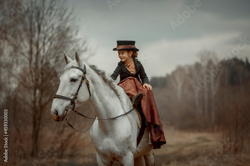 Little girl in riding habit with horse and vizsla in spring forest