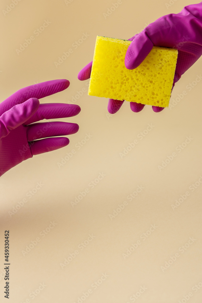 Hand in multi-colored rubber gloves hold a dishwashing sponge, cleaning concept Hand in multi-colored rubber gloves hold a dishwashing sponge, cleaning concept