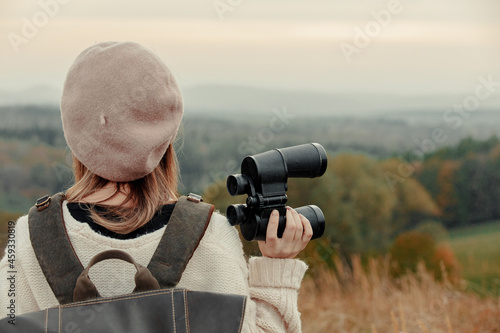 Style girl with binoculars and backpack at countryside