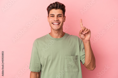 Young caucasian man isolated on pink background showing number one with finger.