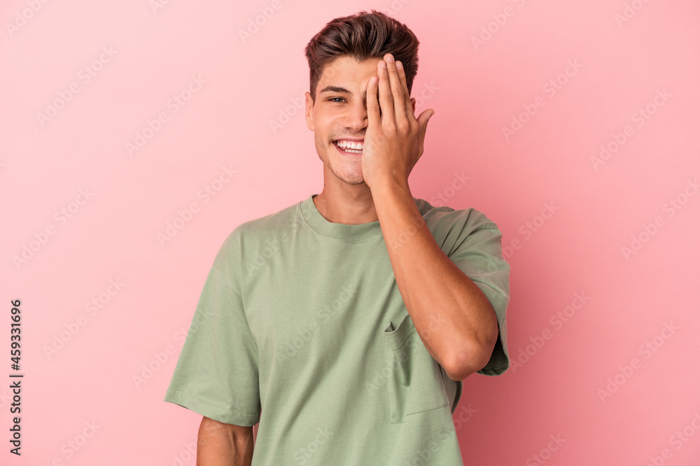 Young caucasian man isolated on pink background having fun covering half of face with palm. Young caucasian man isolated on pink background having fun covering half of face with palm.