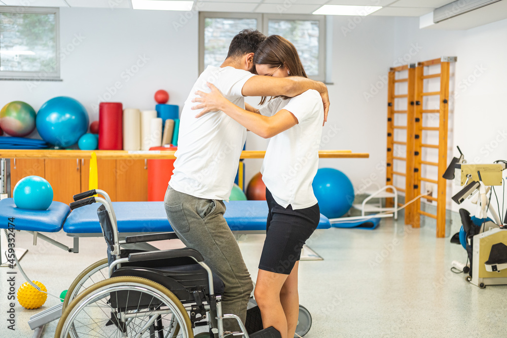 Disabled patient and female physiotherapist, exercise standing up and proper lifting technique