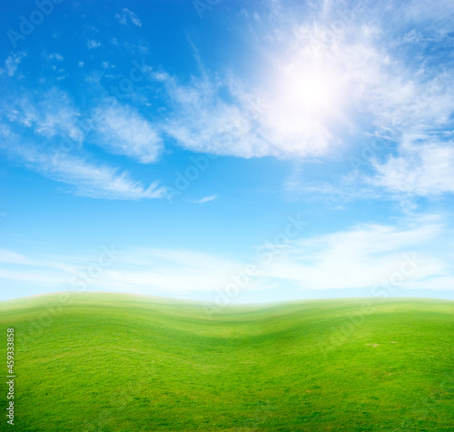 Green grass hills under blue sky.
