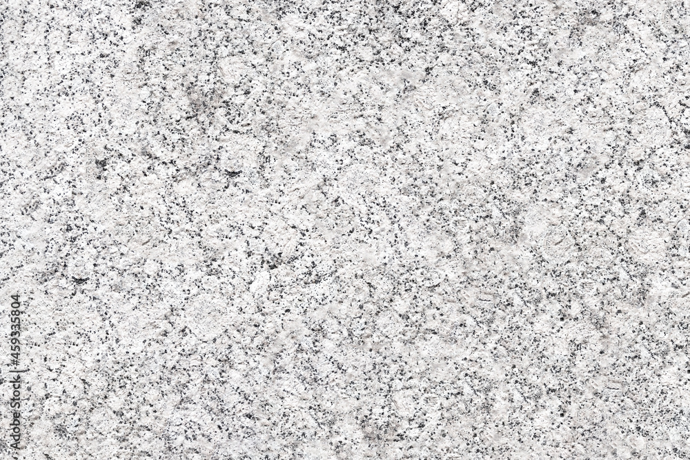 The mottled surface of the granite slab is finely speckled. Uniform texture of natural stone.