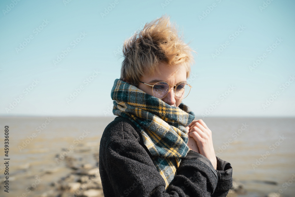 Young female in glasses warming herself on a beach