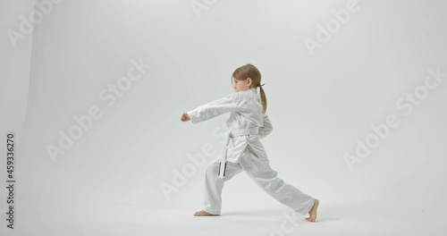 The girl stands in the lunge and strikes with her hands straight. The girl is turned to the side. Video of a girl in full growth.