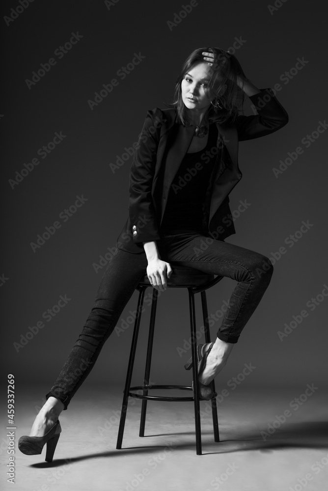 caucasian adult stylish girl on a chair on gray background caucasian adult stylish girl on a chair on gray background