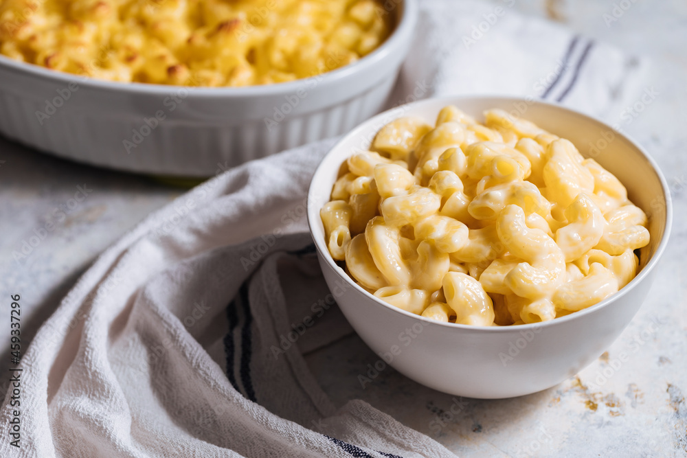 Mac and cheese with basil on top on a rustic wooden board Mac and cheese with basil on top on a rustic wooden board