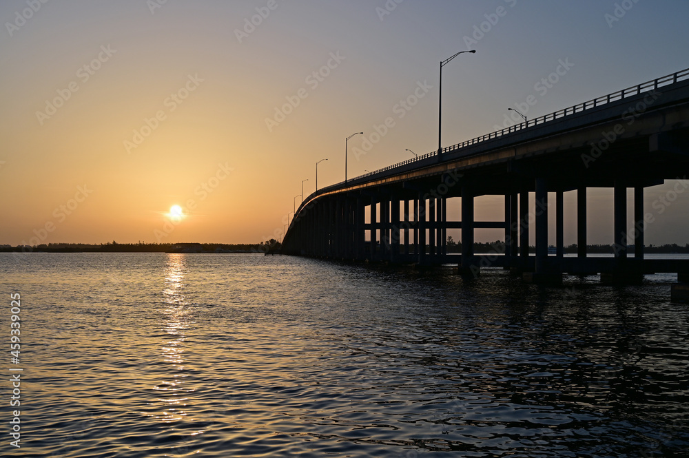 Rickenbacker Causeway Bridge in Miami, Florida under orange sky as sun rises.
