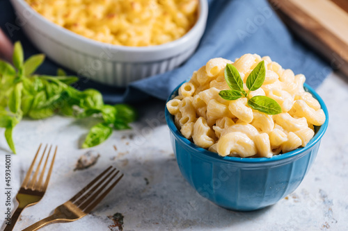 Mac and cheese with basil on top on a rustic wooden board