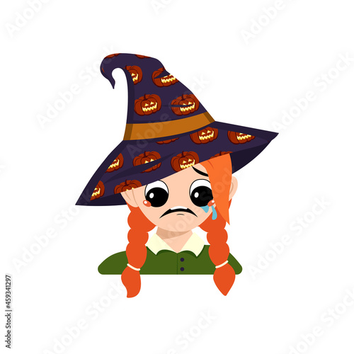 Girl with big eyes and depressive emotion, crying, tears face in a pointed witch hat with pumpkin. The head of a toddler with sad face. Halloween party decoration