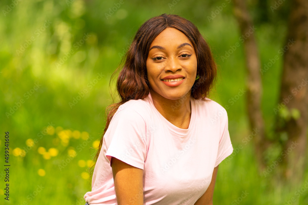 young black woman sitting on a bench in a park on a summer afternoon. young black woman sitting on a bench in a park on a summer afternoon.