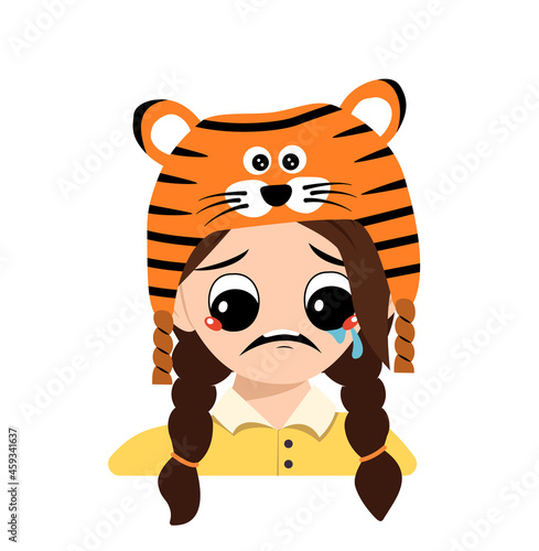 Girl with big eyes and depressive emotion, crying, tears face in tiger hat. Cute kid with sad face in a festive costume for New Year, Christmas and holiday. Head of adorable child with emotions