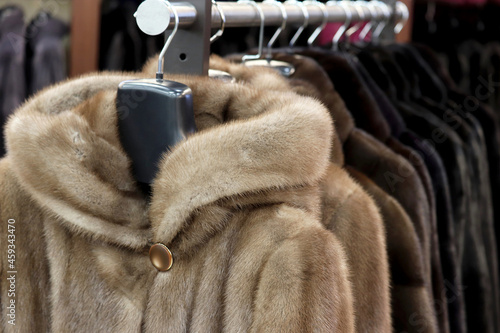 Fur coats in a row on a hanger in the store. Female fashion, natural fur clothes from mink in sale photo