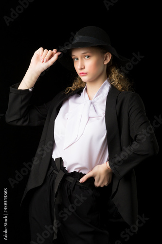 Confident girl teenager posing black suit and hat © lotosfoto