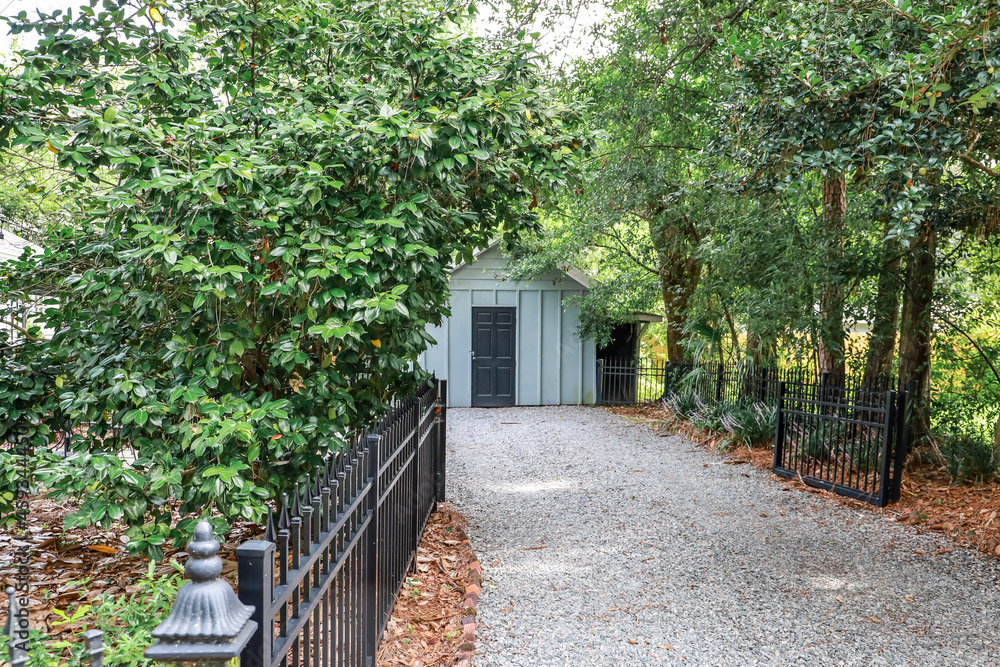 Long driveway with blue outdoor shed wood building for storage and a fence