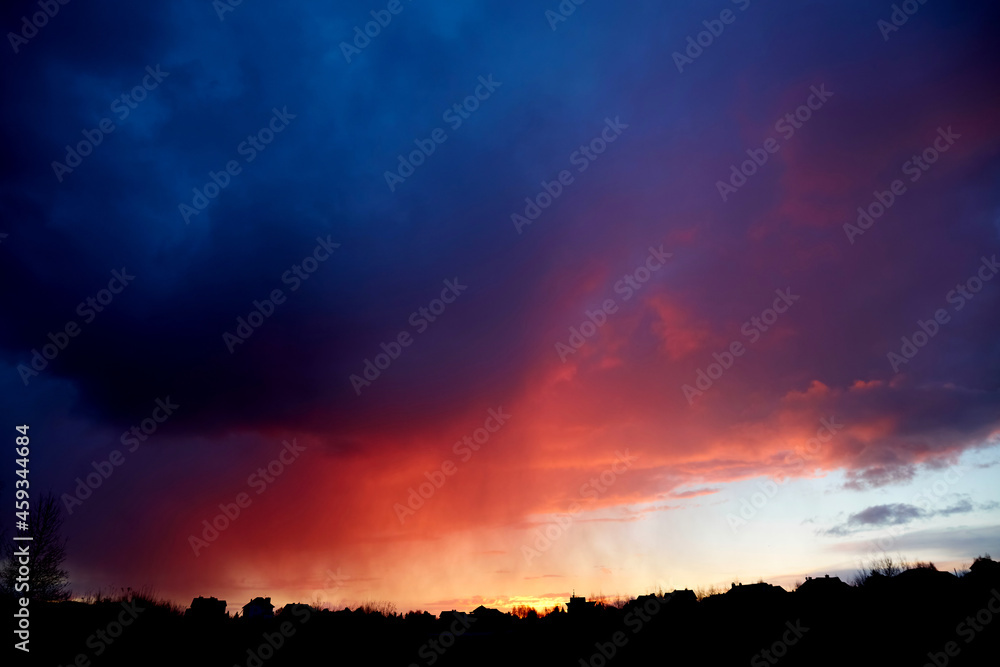 Beautiful fiery red sunset. Evening landscape. Bright color over the black plain horizon. Cloudy weather. Scenic cloudscape. Dramatic sky. Copy space. Wallpaper. Storm wind. Summer thunderstorm