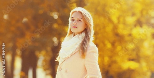 Portrait of beautiful young woman looking at camera in sunny autumn park