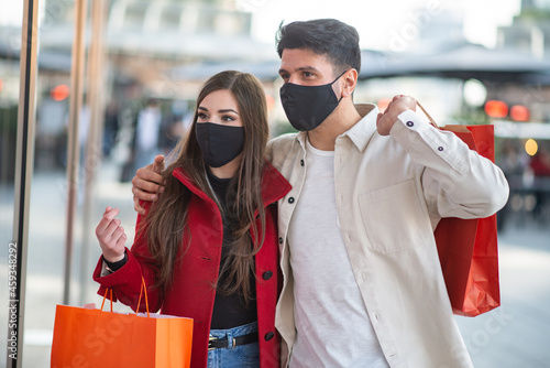 Covid and coronavirus shopping, couple walking in a city while carrying shopping bags