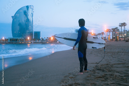 Photography From the back silhouette portrait of surfer standing and holding his surf board,